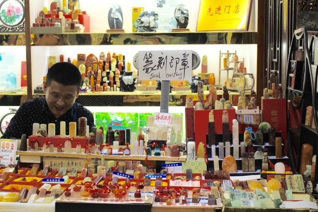爱晚亭旁,一家卖纪念品店铺里的刻印章大叔。